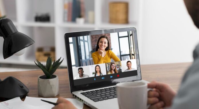 Compact German for Work: A young man sits in front of his laptop and sees his course group in a live video conference.