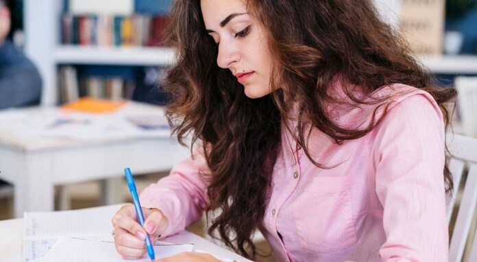 Einbürgerungstest: Eine Frau sitzt in einem Klassenraum und schreibt einen Test.