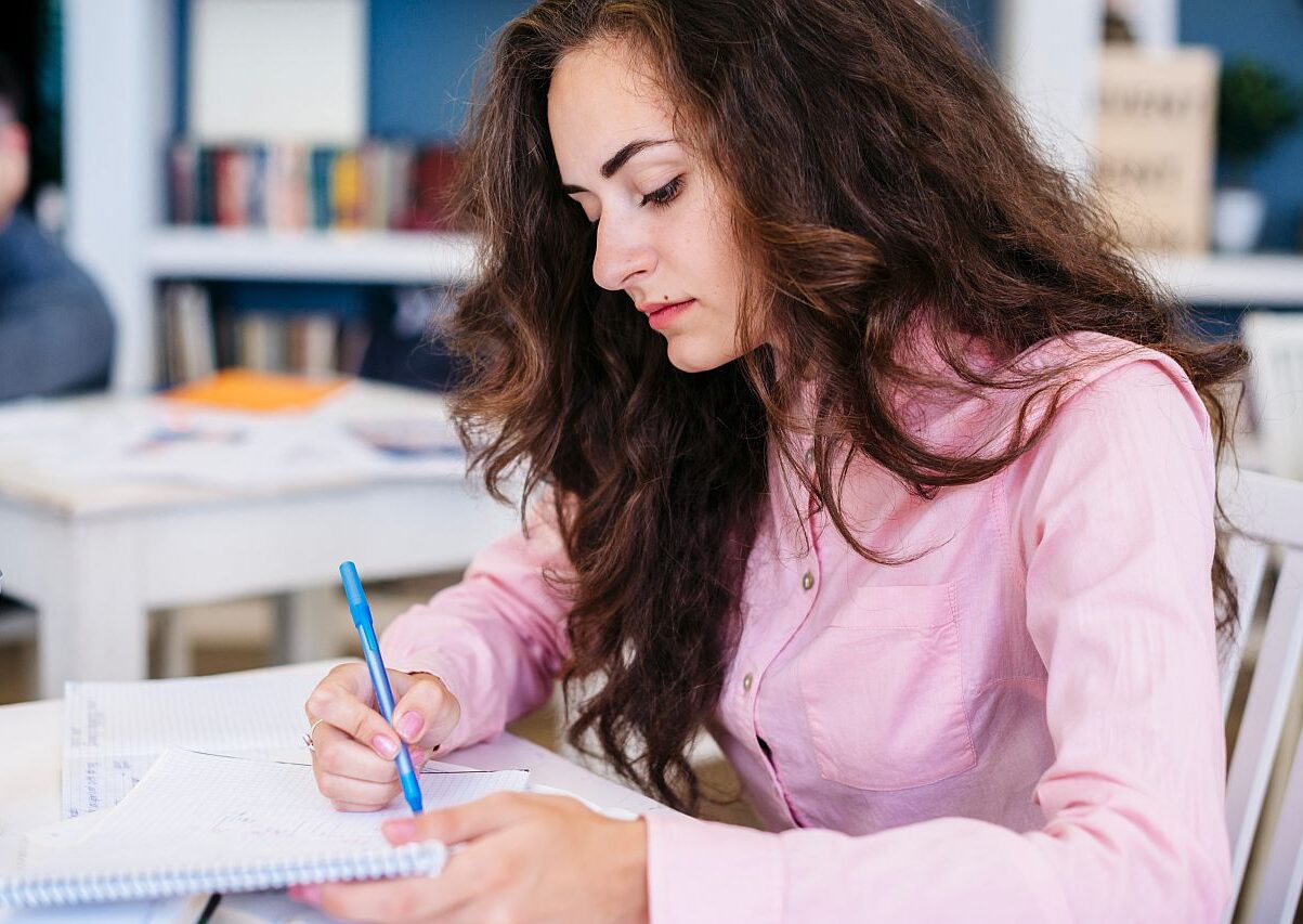 Einbürgerungstest: Eine Frau sitzt in einem Klassenraum und schreibt einen Test.